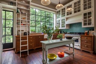 traditional kitchen with wooden cabinetry large crittall windows and farmhouse table islan