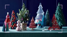 tabletop with a green tablecloth filled with alternative Christmas trees