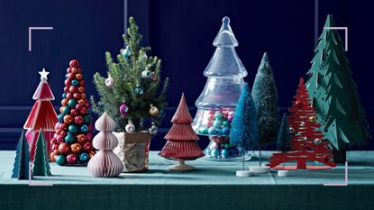 tabletop with a green tablecloth filled with alternative Christmas trees