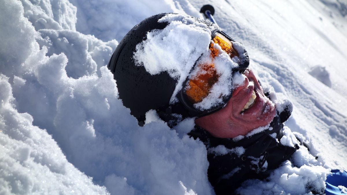 Smiling skier lying in snow after falling