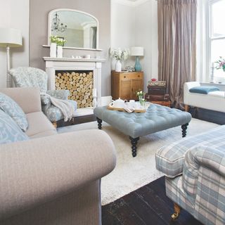 beige and pale blue living room with log storage in fireplace