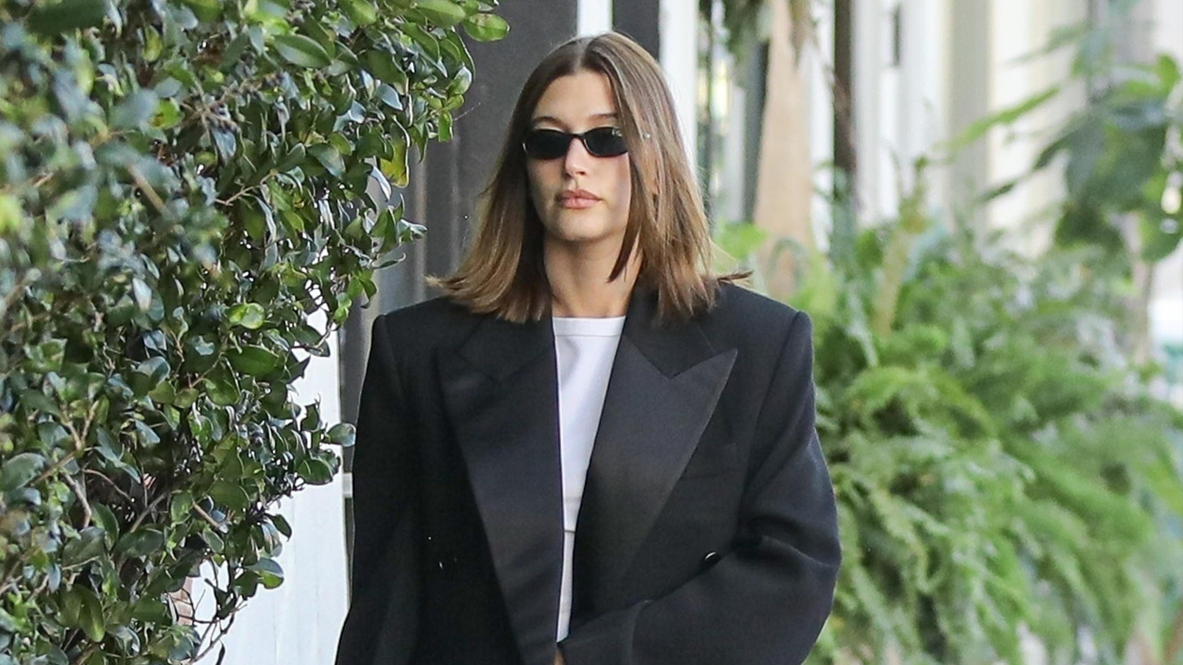 Hailey Bieber wearing a black maxi coat with jeans and The Row Penelope Mules.