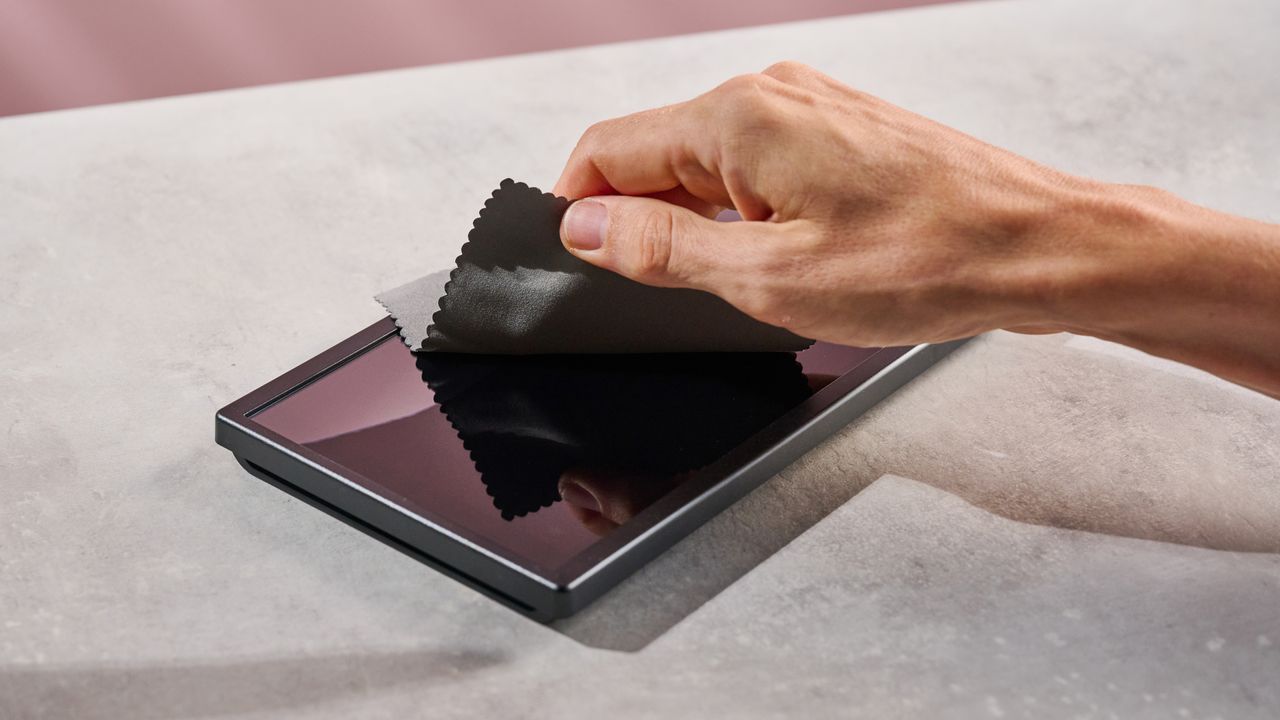 A man wipes down the Belkin Temperd Glass Anti-Reflective Screen protector after applying it to the Nintendo Switch 2.