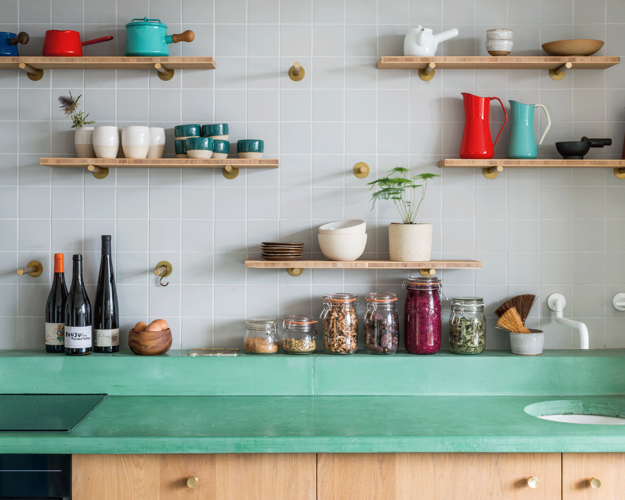 A green concrete kitchen worktop with open shelving above it