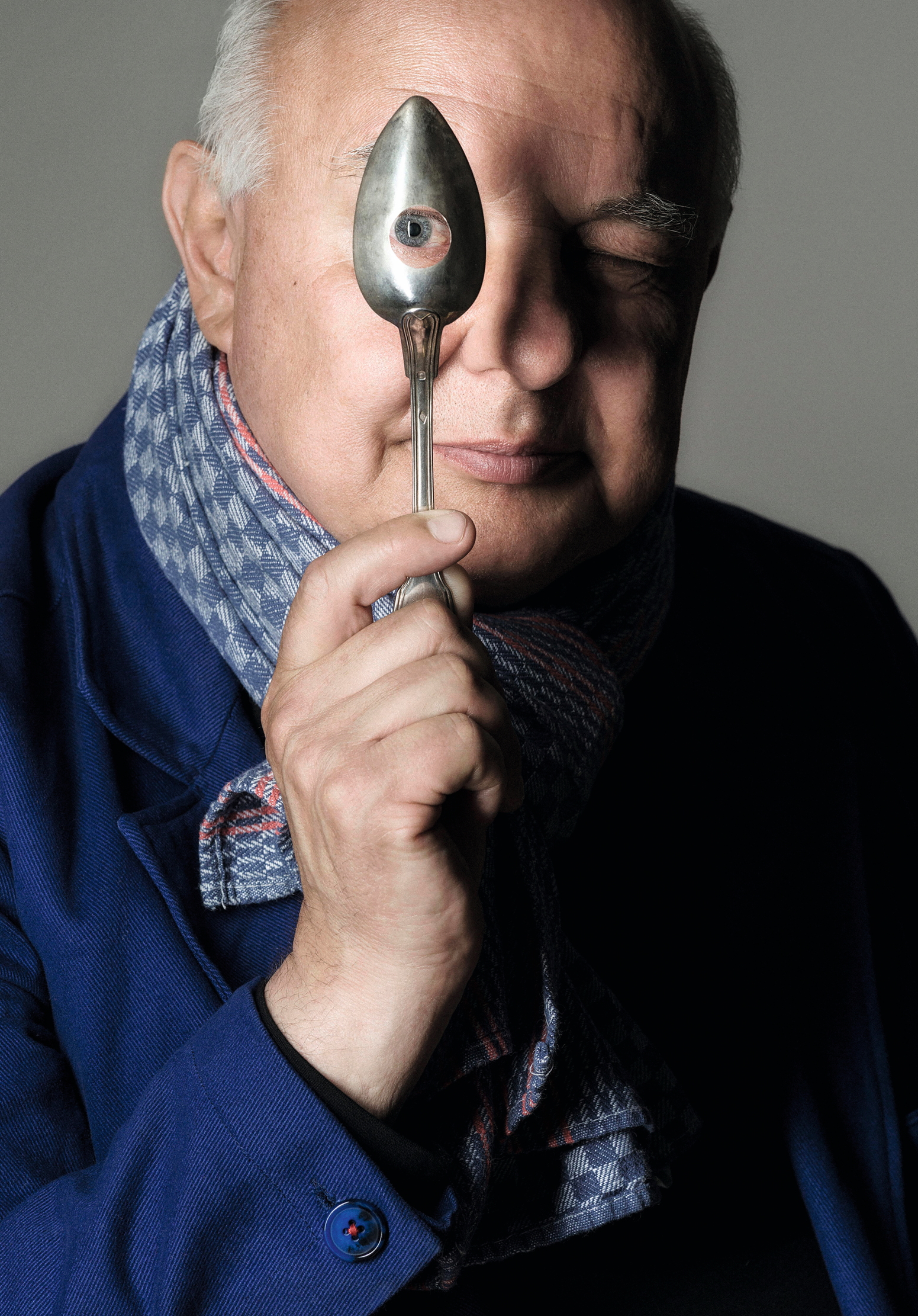 Rolf Sachs stares at the camera through a hole in a spoon.