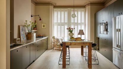 A galley kitchen with warm neutral walls, green cabinets, and a wooden freestanding kitchen island