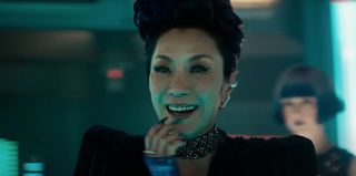 A sinister-looking futuristic woman with long nails is laughing