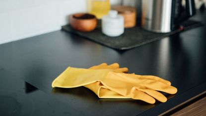 A pair of yellow washing up gloves on a black kitchen counter