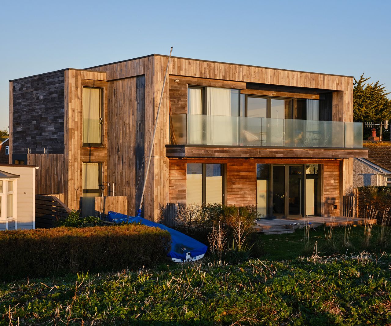 A contemporary seaside home clad in timber with a balcony on the first floor