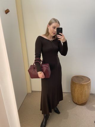 Woman wears brown knit dress, burgundy bag and black boots