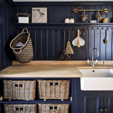 navy blue kitchen wall with wooden worktop, white sink, storage hooks and storage baskets