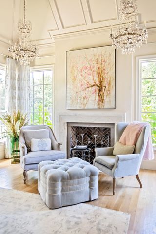 cream living room with paneled ceiling grey armchairs and footstool fireplace and chandelier