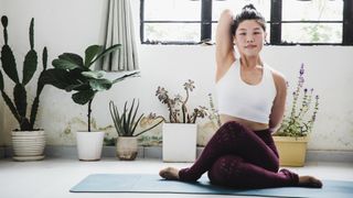 Woman sat on yoga mat performing cow-face pose