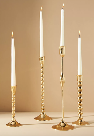 four gold candlesticks in different twisted designs and heights