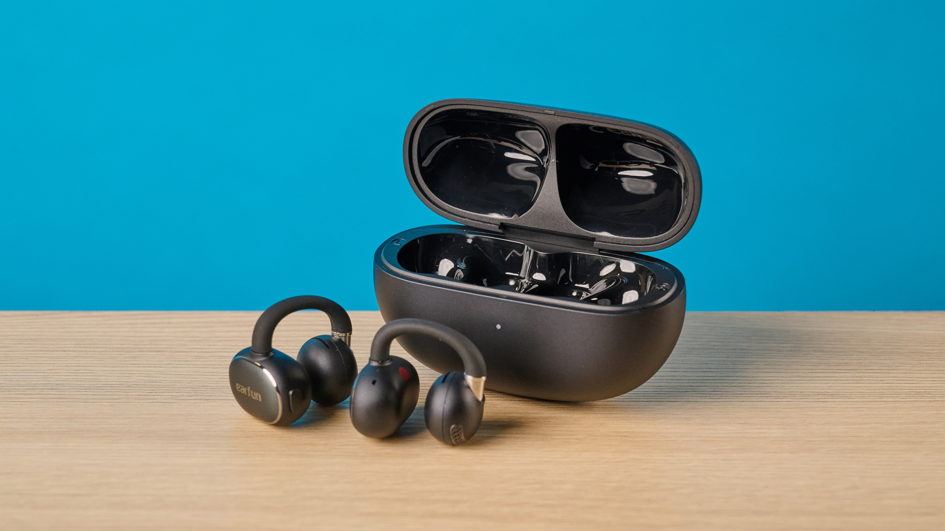 EarFun Clip 2 in black on table photographed in front of a blue background