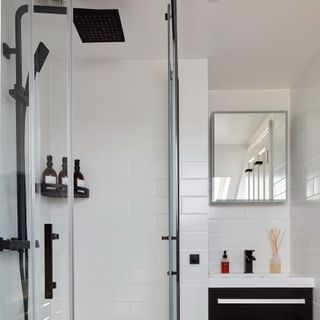 A white-tiled bathroom with a shower and shower shelf for toiletries