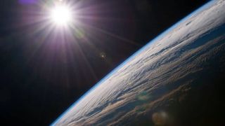 the sun rises above Earth as seen from a space station in orbit
