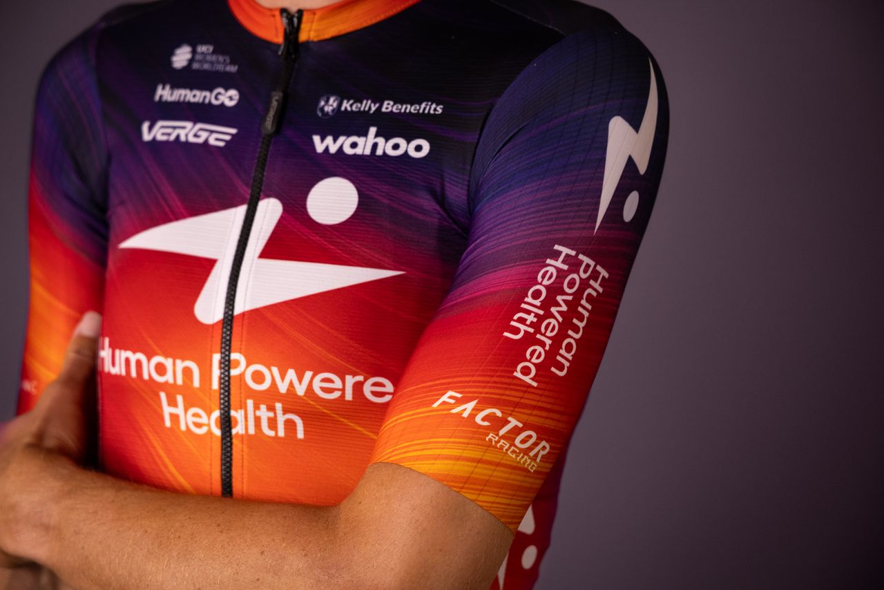 Human Powered Health riders pose in new 2026 team kit, a blend of purple and orange