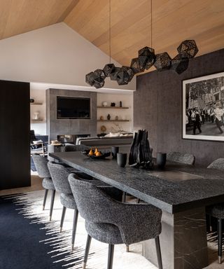 Modern dining room with wooden paneled ceiling, large gray marble dining table, gray chairs,