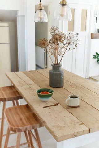 rustic dining room with rustic table, pot on the table with dried flowers, bar stools