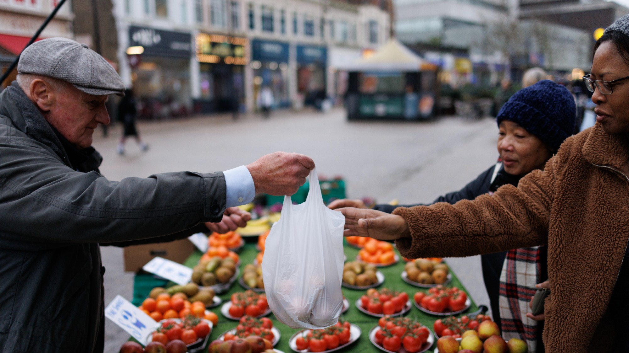 A customer buys produce from a market stall holder on a fruit and veg stand in Bromley