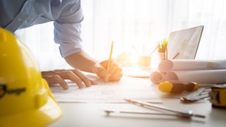 Builder with yellow hard hat examining work plans