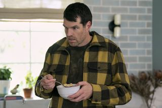 Timothy Simons as Sasha, standing in a kitchen and holding a bowl of cereal, in episode 104 of Nobody Wants This