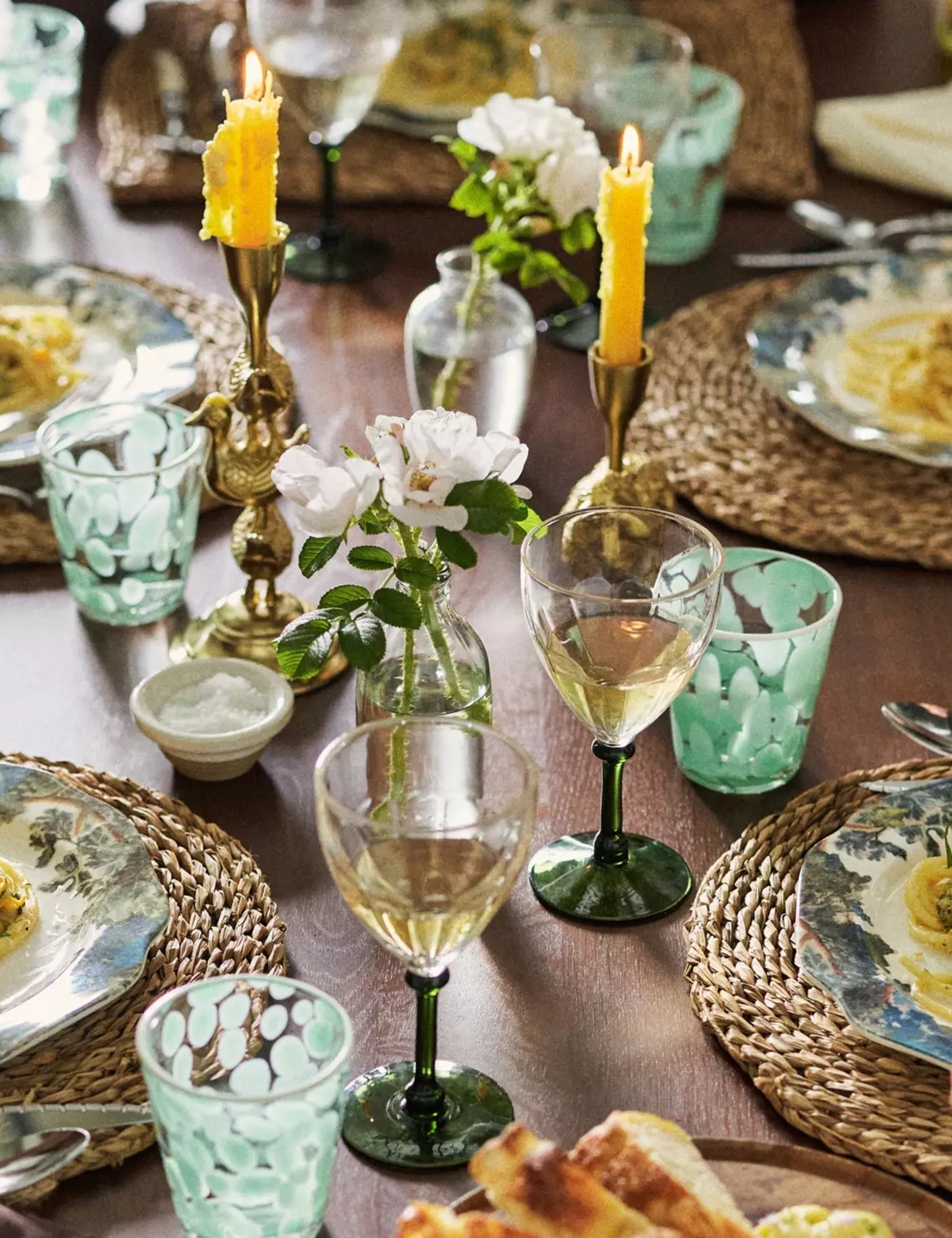 Botanically-inspired Thanksgiving table styled with green-and-clear wine gablets, Judarn-print plates, and woven chargers.