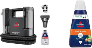 upholstery cleaner in black with attachments showing alongside a blue and orange bottle of spot and stain