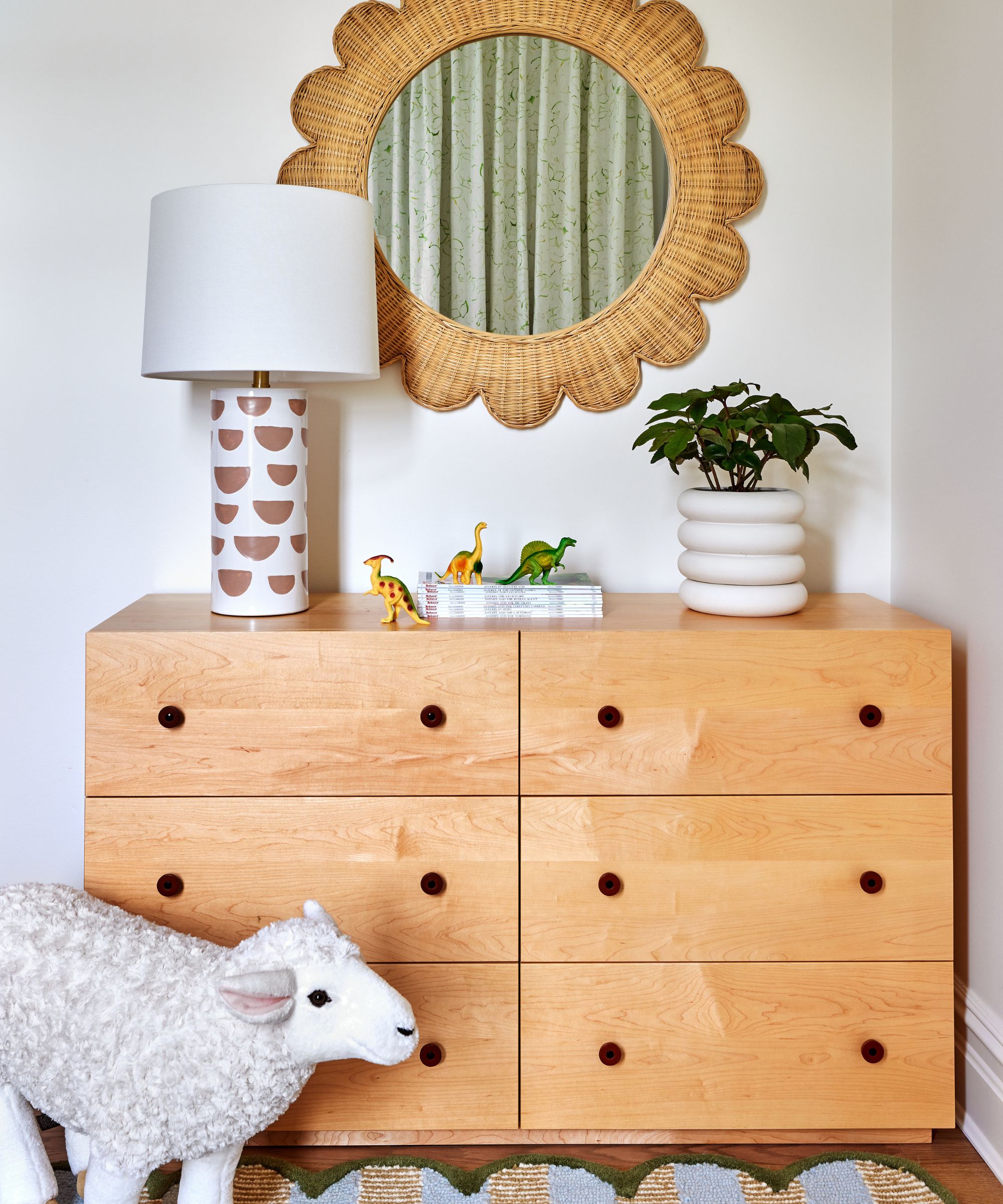 Nursery with wood dresser, rattan mirror, plant pot and ceramic lamp