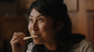 A woman holds up a pair of chopsticks to her mouth