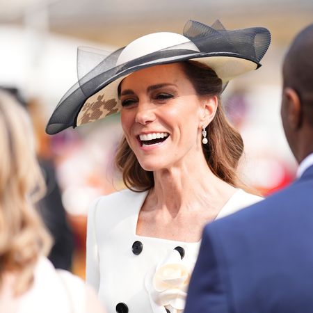Princess Kate wearing a white hat smiling at guests at a garden party