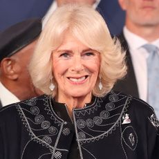 Queen Camilla smiling in a blue robe 