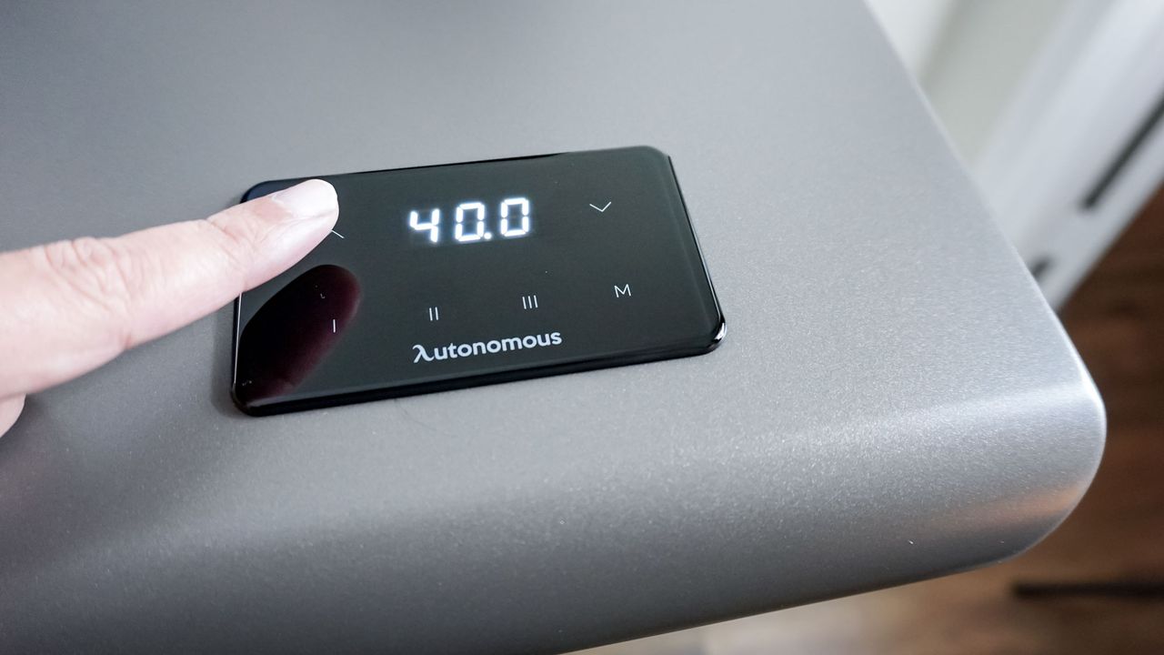 A finger hovering over the Autonomous SmartDesk 5's integrated touch-sensitive control pad