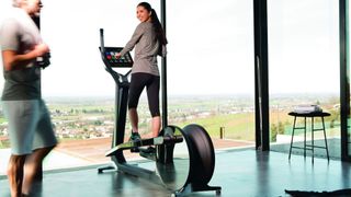 Woman using an elliptical in front of large mirrors