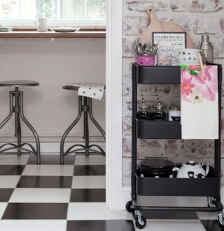 kitchen with brick wall black kitchen trolley and black and white floor