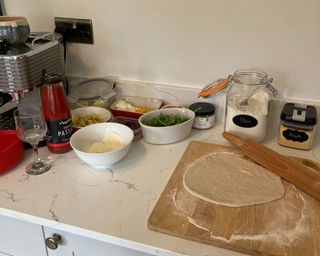 making pizza in a kitchen with all of the ingredients and base ready