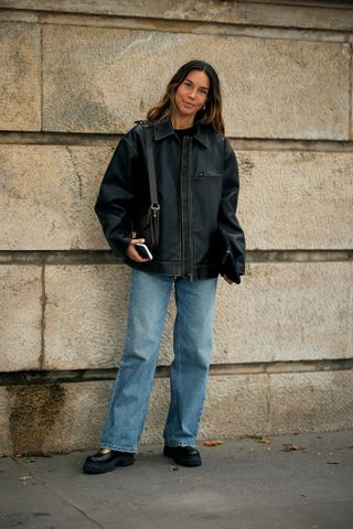 Influencer wears black leather bomber jackets with jeans.