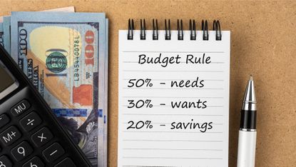A notepad with 50-30-20 budgeting rules on it next to a calculator and cash. 