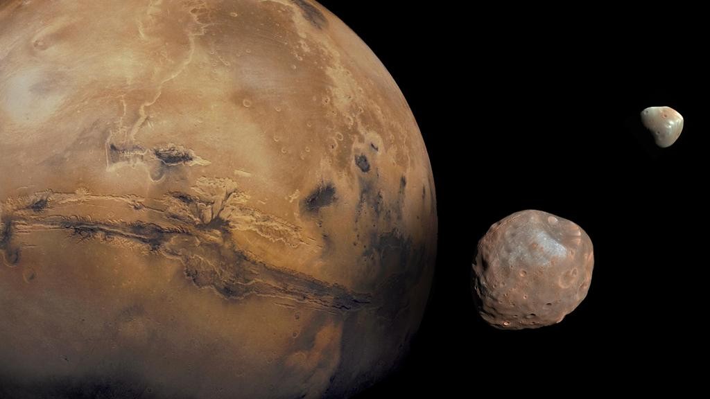 यहां हम मंगल ग्रह और उसके दो गड्ढों वाले चंद्रमाओं को देखते हैं - फोबोस नामक एक आंतरिक चंद्रमा और डीमोस नामक एक छोटा बाहरी चंद्रमा।