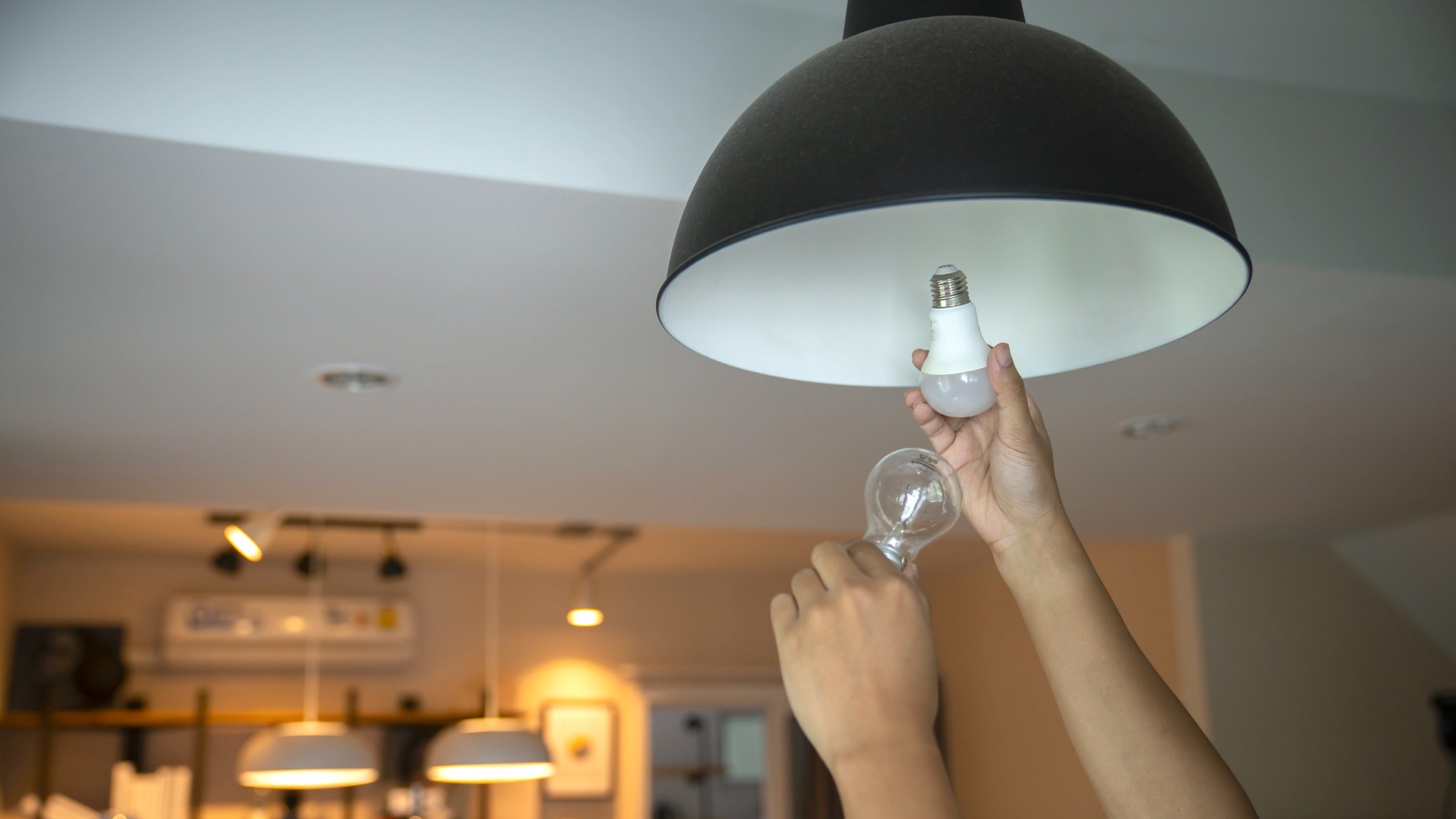 Person replacing regular light bulb with smart bulb