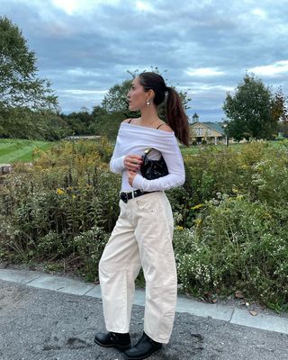 @anna_laplaca wearing white top, cream jeans, and black accessories
