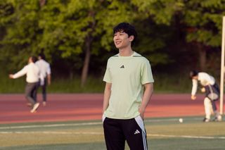 Joshua Hyunho Lee as Jin standing on a soccer field in episode 202 of XO, Kitty.