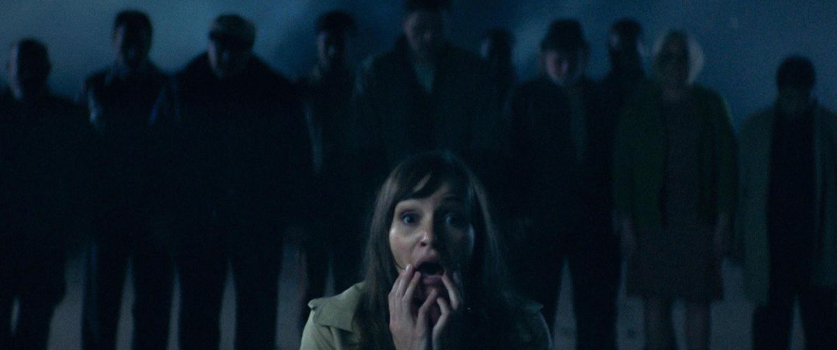 A woman screams in front of a shadowy group of people