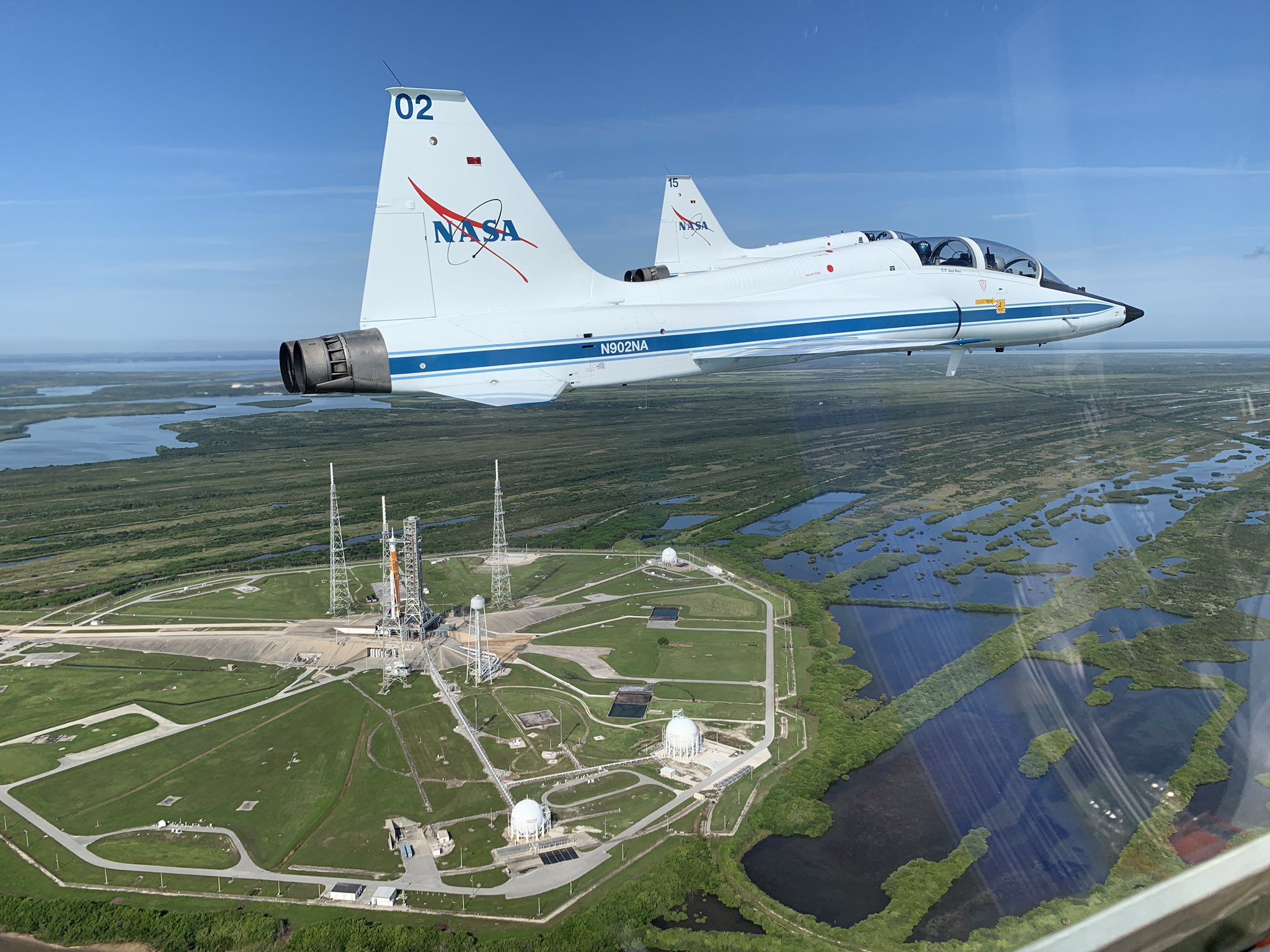 T-38 jets fly past NASA's SLS rocket at Kennedy Space Center.