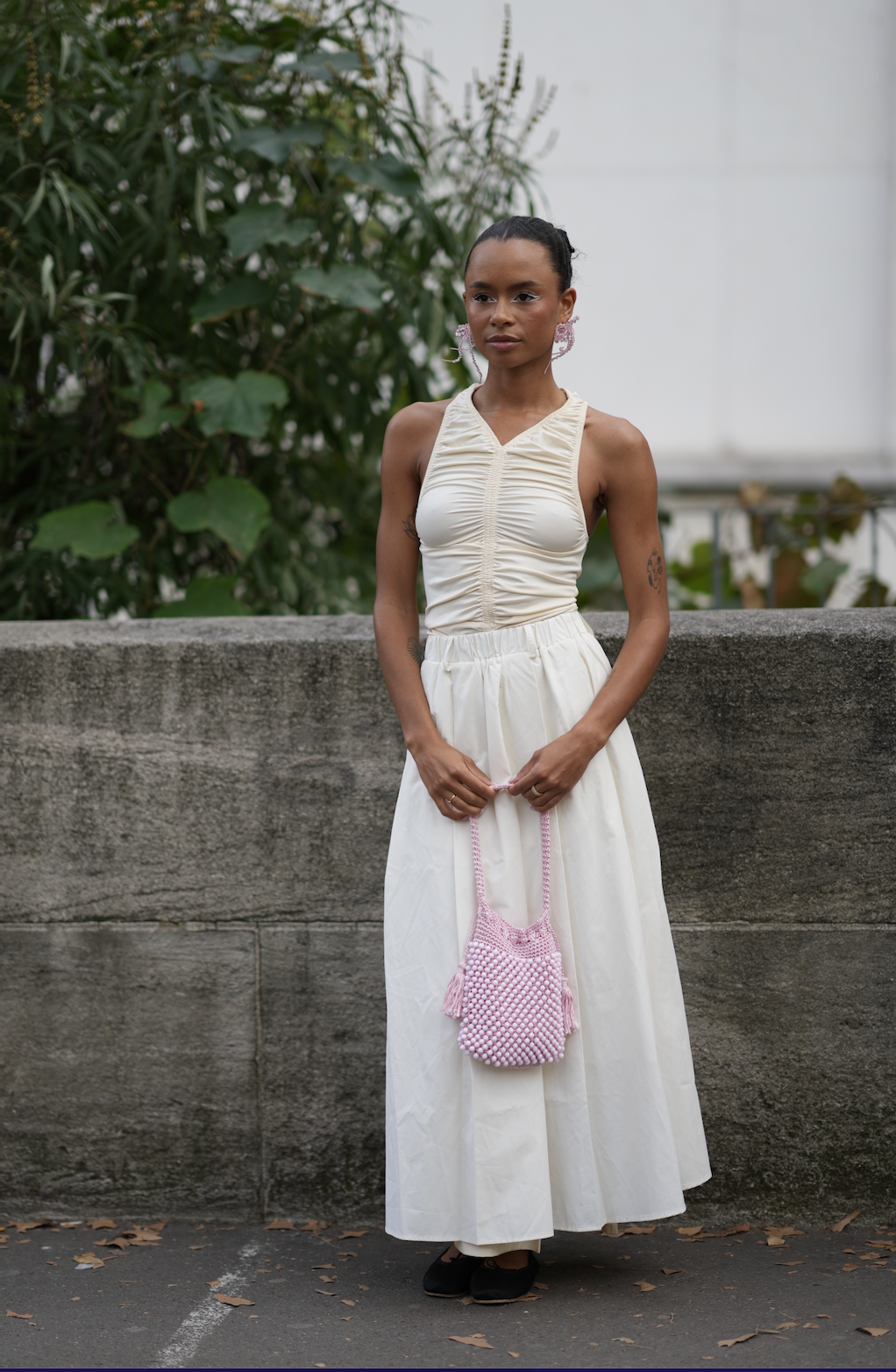 woman wears all white and a purple beaded bag