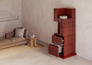 A living space with a day bed and a red, sculptural shaped fridge with open drawers