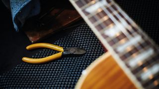 An electric guitar being set up with a pair of string cutters in the background