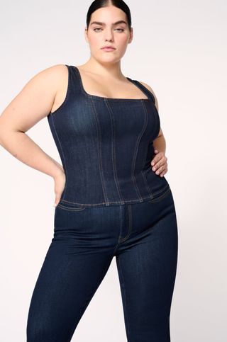 Model wears dark wash denim tank and matching slim fit jeans 