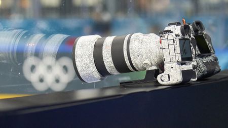 A Sony camera with a mounted lens and battery grip wearing a black and white patterned skin. A second Sony camera wearing a black patterned skin sits behind it